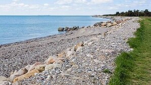 A pebbled beach with a grassy area on one side and a clear blue sky. - 4 Person Holiday Home in Hurup Thy-by Traum (Hurup Thy)