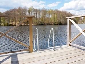 A wooden dock with metal ladders and railings, leading to a calm lake surrounded by trees. - 4 Person Holiday Home in Kyrkhult (Kyrkhult)