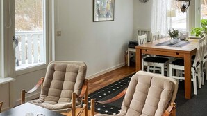 A dining area with a wooden table and chairs, a black table with glasses, and a view of a deck through a window. - 4 Person Holiday Home in Nordkoster (Stromstad)