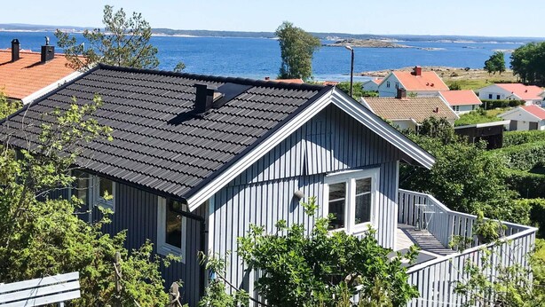 A house with a dark roof, white windows, and a view of the sea. - 4 Person Holiday Home in Nordkoster (Stromstad)
