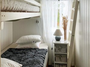 A bunk bed with a pillow and a bedside table with a lamp and baskets. - 4 Person Holiday Home in Nordkoster (Stromstad)