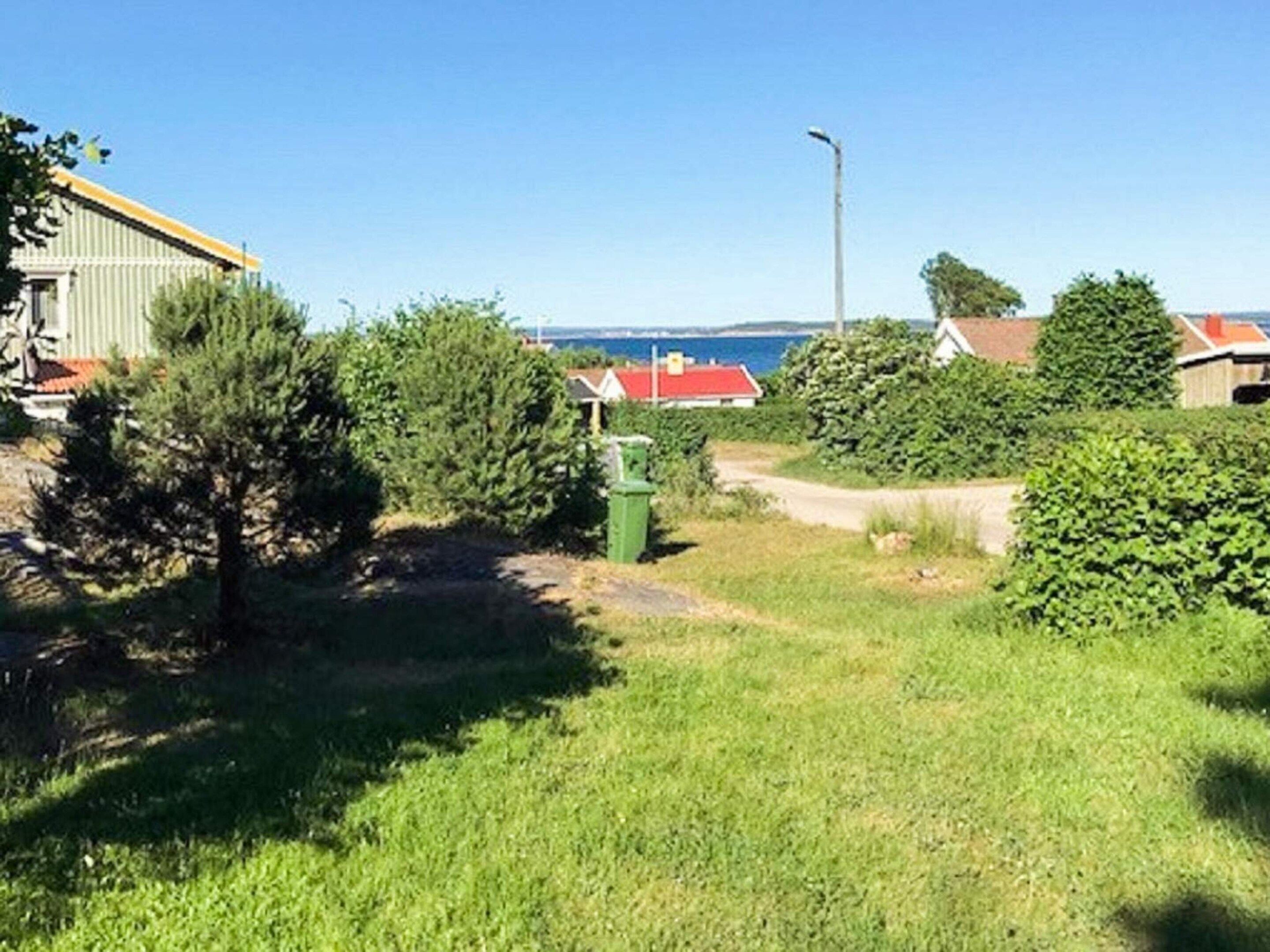 Une zone herbeuse avec un sentier menant à un bâtiment doté d’un toit rouge.