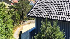 A residential area with a house featuring a tiled roof and a wooden deck. - 4 Person Holiday Home in Nordkoster (Stromstad)