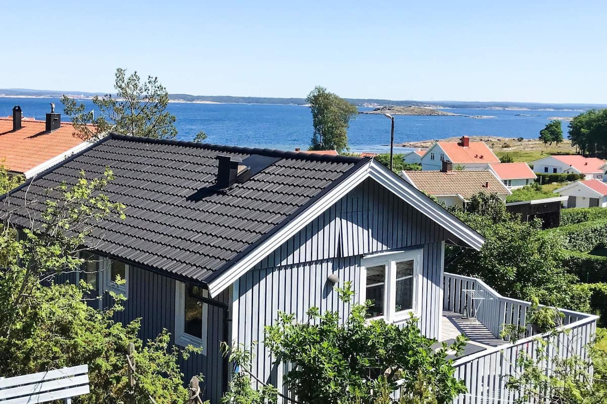 A coastal house with a dark roof, white windows, and a small porch.