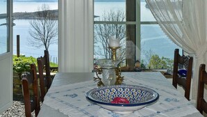 A dining area with a table set for two, a decorative bowl, and a view of a lake. - 4 Star Holiday Home in Onarheim (Tysnes)