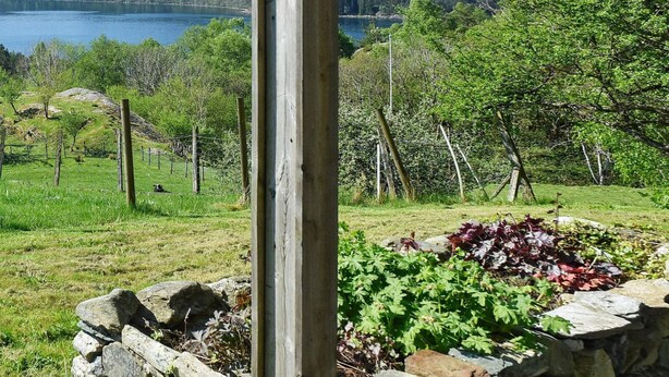 A rural landscape with a wooden post, stone wall, and a fenced area with vegetation. - 4 Star Holiday Home in Onarheim (Tysnes)