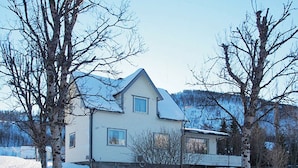 A two-story house with a gabled roof, a front porch, and a fenced yard.