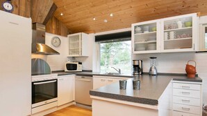 A modern kitchen with white cabinetry, stainless steel appliances, and a wooden ceiling.