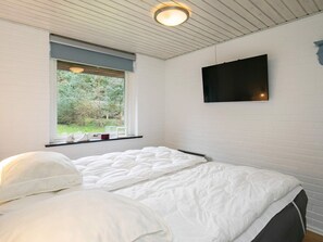 A bedroom with a bed, a window with a view of greenery, a mounted TV, and a ceiling light fixture. - 6 Person Holiday Home in Ulfborg (Ulfborg)
