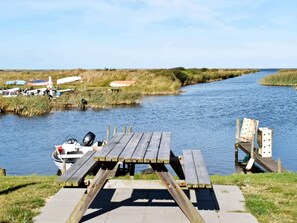 Une jetée en bois s’étendant dans un fleuve paisible, avec des bateaux amarrés à proximité.