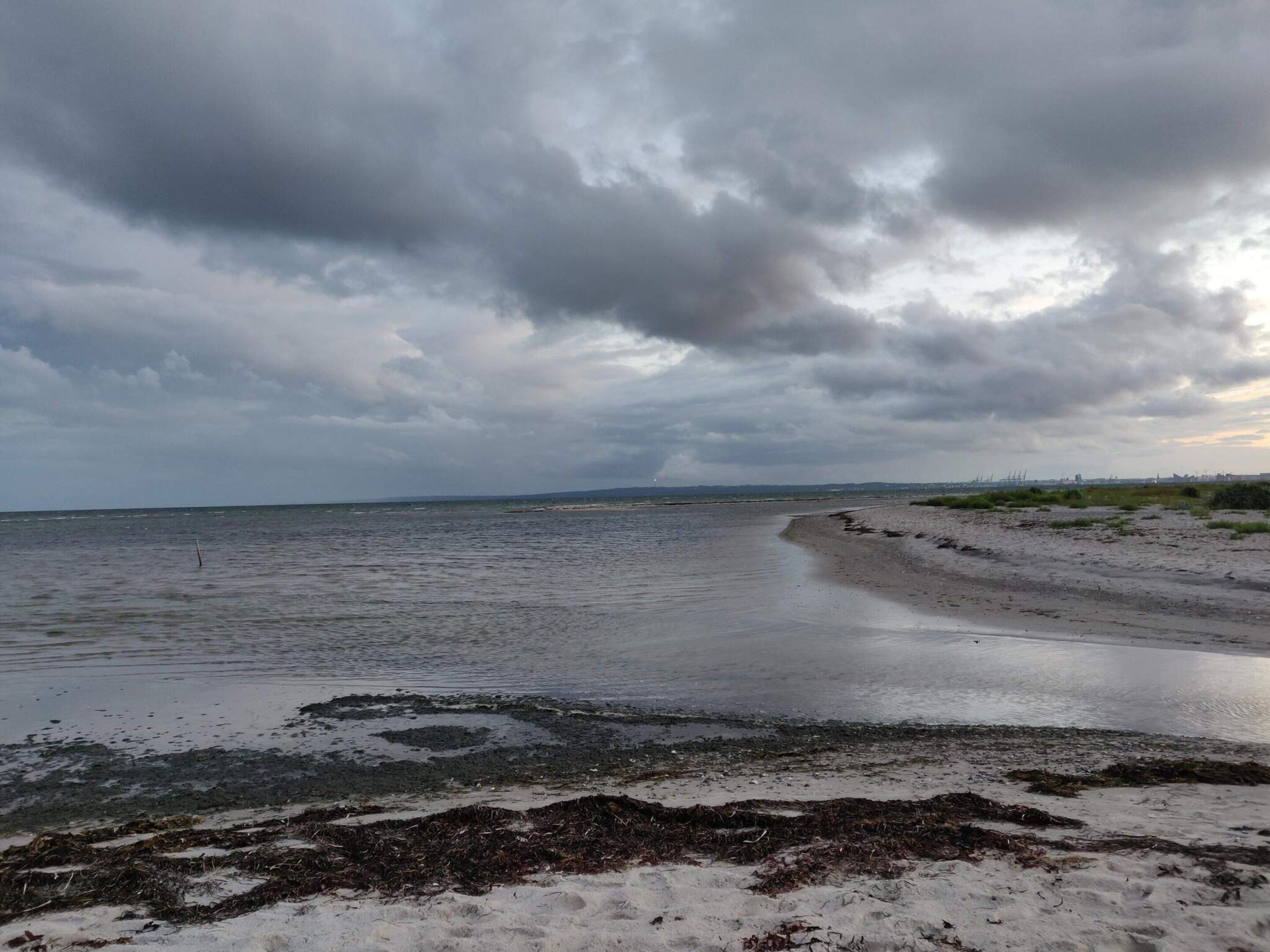 Una playa con una extensa zona arenosa y una masa de agua.