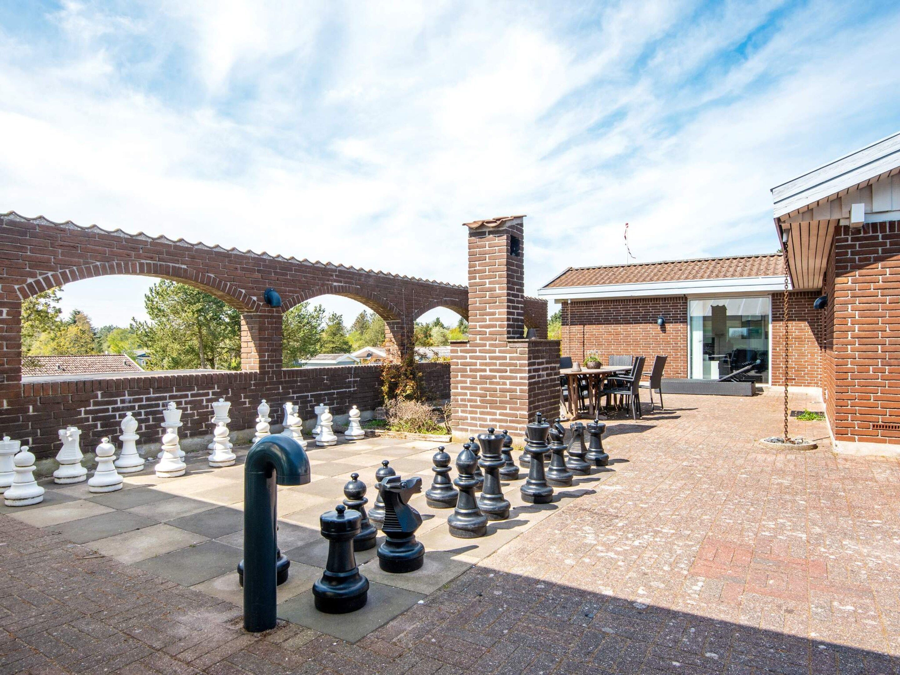 Un patio con un tablero de ajedrez dispuesto y un edificio de ladrillo con puerta de cristal.