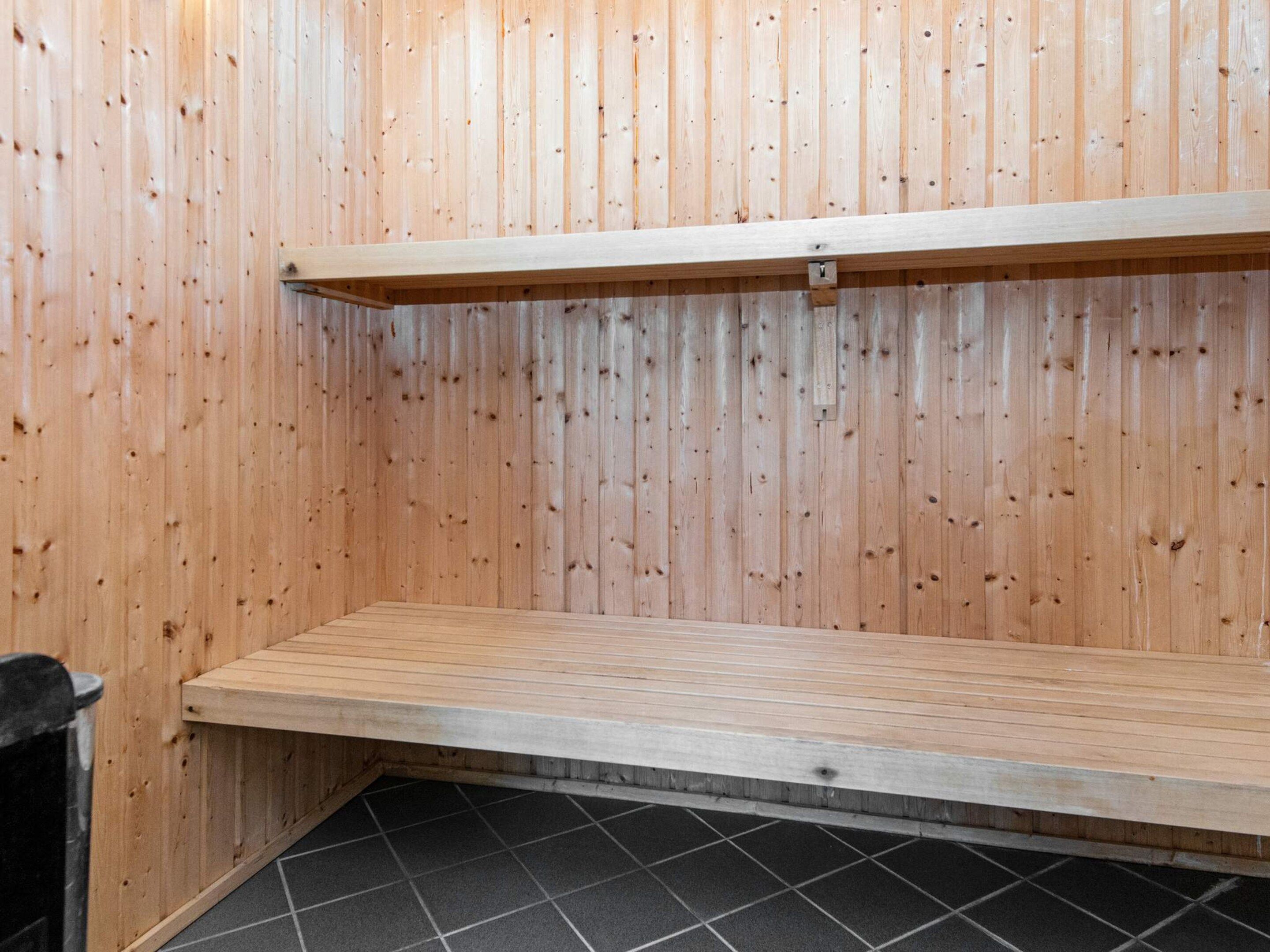 Een houten sauna met een bank en een plank.