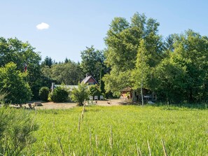 A rural landscape with a red house, a wooden cabin, and a field of tall grass. - 6 Person Holiday Home in Braedstrup (Braedstrup)