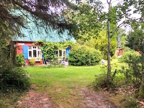 A house with a blue roof and red walls, surrounded by lush greenery and a well-maintained lawn. - 6 Person Holiday Home in Braedstrup (Braedstrup)