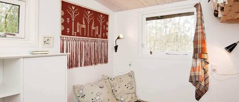 Une chambre confortable avec un lit, une fenêtre, une lampe fixée au mur et un tapis à motifs.