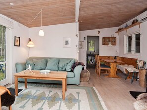 A cozy living room with a sofa, a wooden coffee table, and a dining table with chairs. There is a kitchen area visible in the background. - 4 Person Holiday Home in Bryrup (Bryrup)