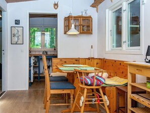 A wooden dining area with a bench and chairs, a cabinet with glass doors, and a window with a view of greenery.