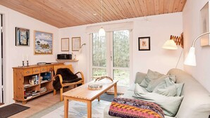 Una sala de estar acogedora con techo de madera, un sofá, una mesa de centro y una estantería.