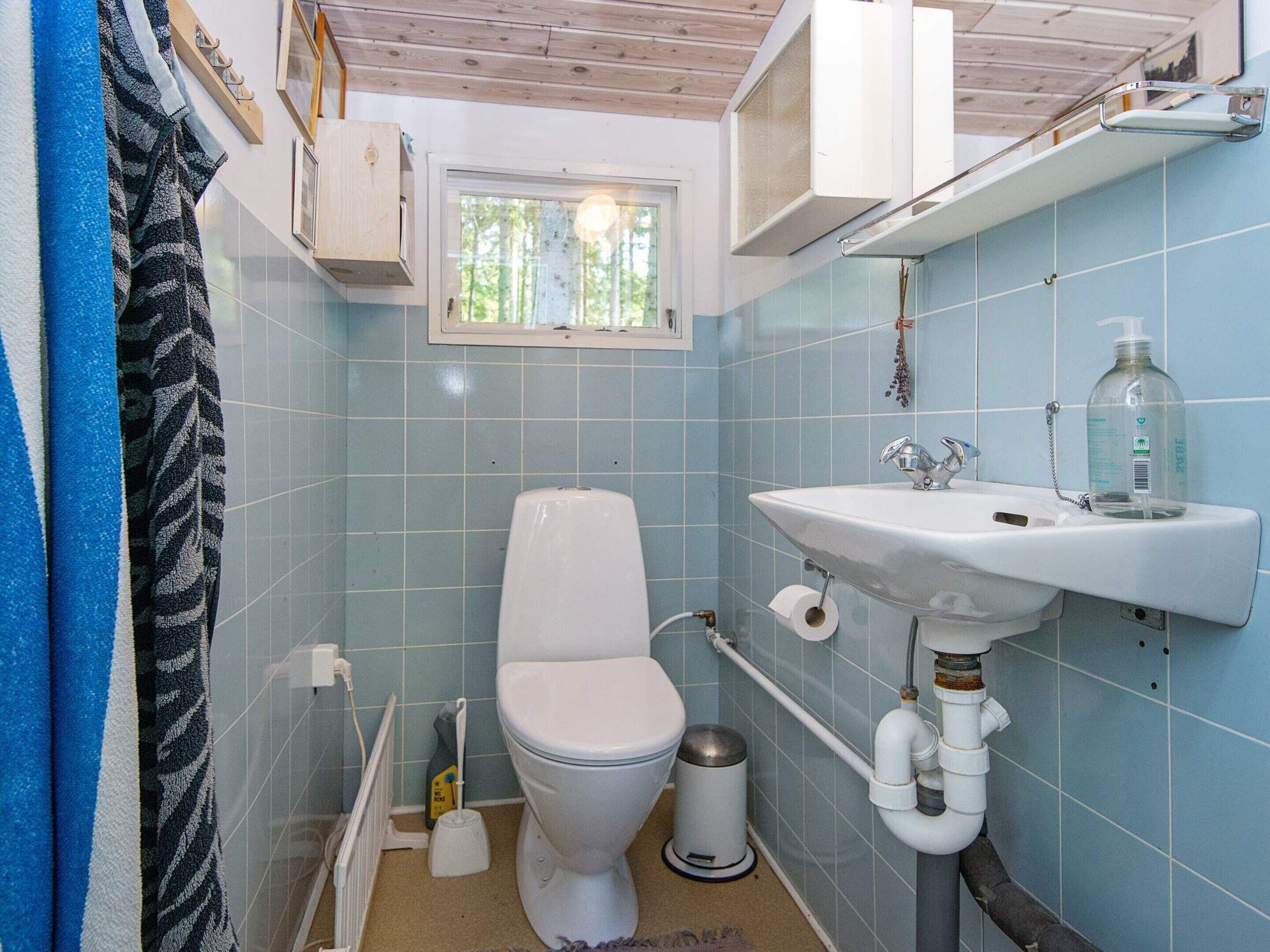 Une petite salle de bain avec des toilettes, un lavabo et une fenêtre.
