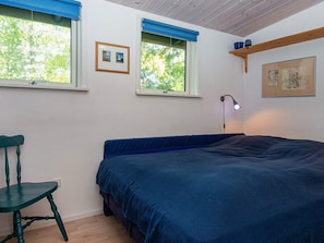 A bedroom with a bed, a chair, two windows with blinds, a wall-mounted shelf, and a floor lamp. - 4 Person Holiday Home in Bryrup (Bryrup)