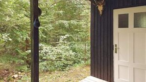 Una cabaña de madera con un trofeo de venado colgado en la pared, rodeada de un bosque frondoso.