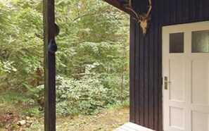 A wooden cabin with a deer head mounted on the wall, surrounded by dense forest. - 4 Person Holiday Home in Bryrup (Bryrup)