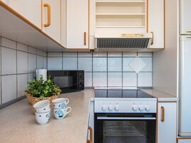 Una cocina con microondas, horno y una planta en la encimera.