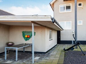 A covered outdoor area with a table, a green net with balls, and a door. - 6 Person Holiday Home in Thyboron (Thyborøn)