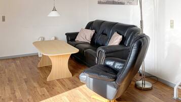 Una sala de estar moderna con un sofá de cuero negro, una mesa de centro de madera y una lámpara de pie.
