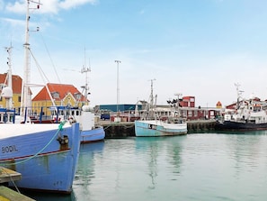 A harbor with boats docked, buildings with red roofs, and a clear sky. - Smart Apartment in Thyborøn near Sea (Thyborøn)