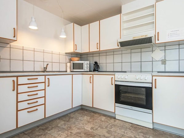 Cocina con alacenas blancas, microondas, horno y lavabo.