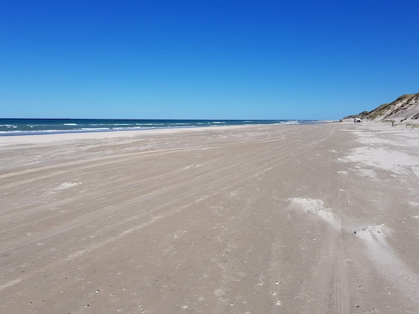 A wide, sandy beach with gentle waves and a clear blue sky. - Luxury Spa Retreat by Golf (Aalbaek)
