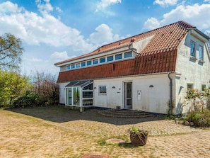 A two-story house with a red-tiled roof, a glass door entrance, and a paved courtyard. - 4 Star Holiday Home in Haderslev (Haderslev)