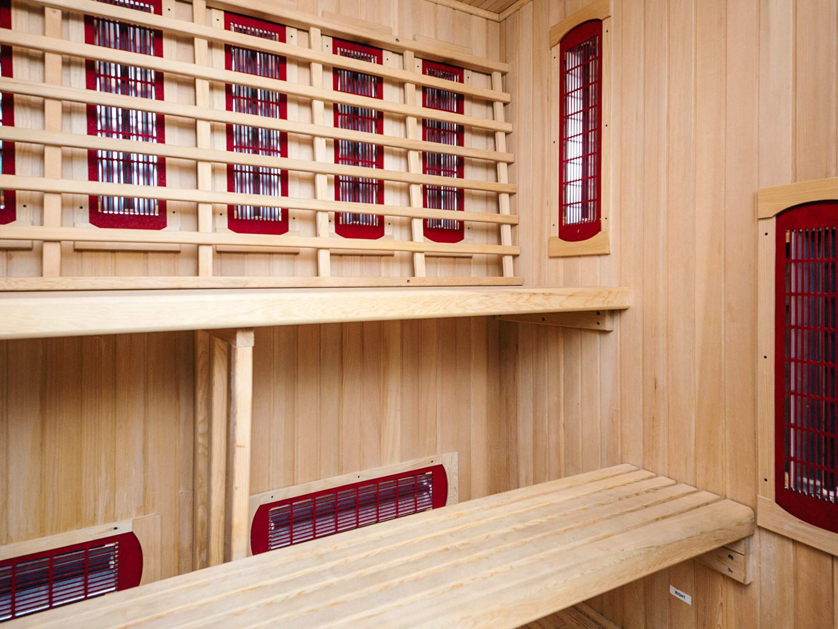 A sauna room with wooden walls, multiple benches, and red-framed windows.