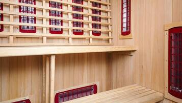 A sauna room with wooden walls, multiple benches, and red-framed windows.