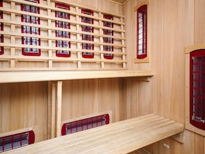 A sauna room with wooden walls, multiple benches, and red-framed windows. - 4 Star Holiday Home in Haderslev (Haderslev)