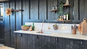 Een keuken met donkere houten kasten, een granieten aanrecht, een spoelbak en diverse keukengerei en apparaten.