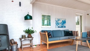Een gezellige woonkamer met een houten bank, een klein tafeltje, een groene hanglamp en een open haard.