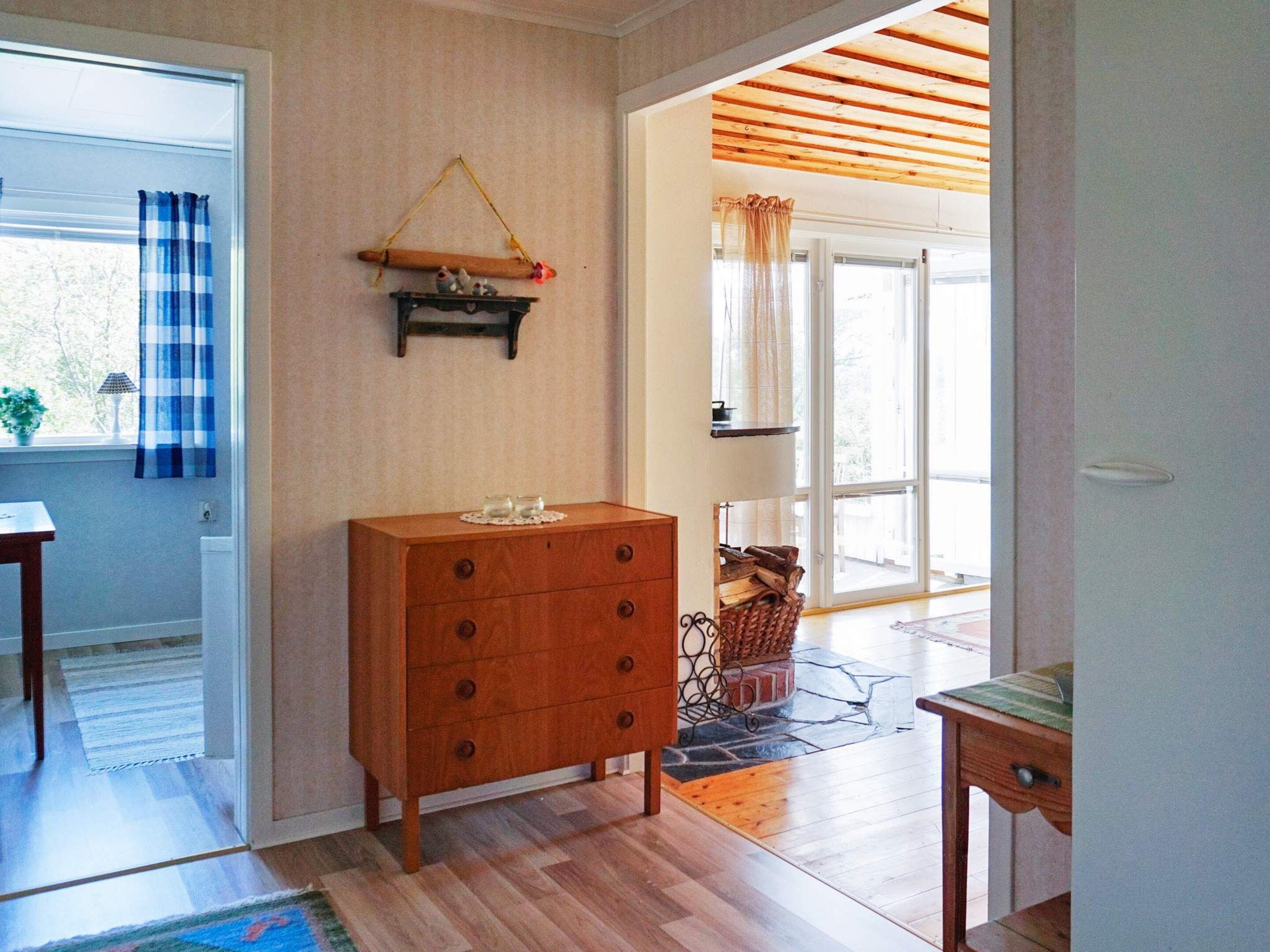 Een kamer met een houten dressoir, een raam met gordijnen, een houten balk en uitzicht op het exterieur.