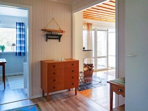 A room with a wooden dresser, a window with curtains, a hanging wooden beam, and a view of the outside. - 5 Person Holiday Home in Munkedal (Munkedal)