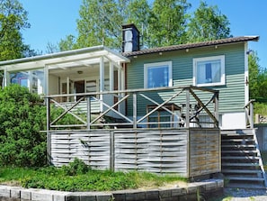 A two-story house with a covered porch and a wooden deck. - 5 Person Holiday Home in Munkedal (Munkedal)