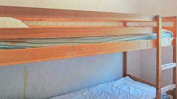 A bunk bed with a wooden frame and a lower bed with a white mattress.