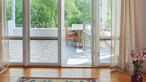 Una habitación con una puerta corrediza de vidrio que da a un patio exterior con una mesa y sillas de madera.