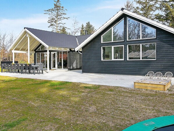 A modern house with a covered patio, large windows, and a well-maintained lawn.