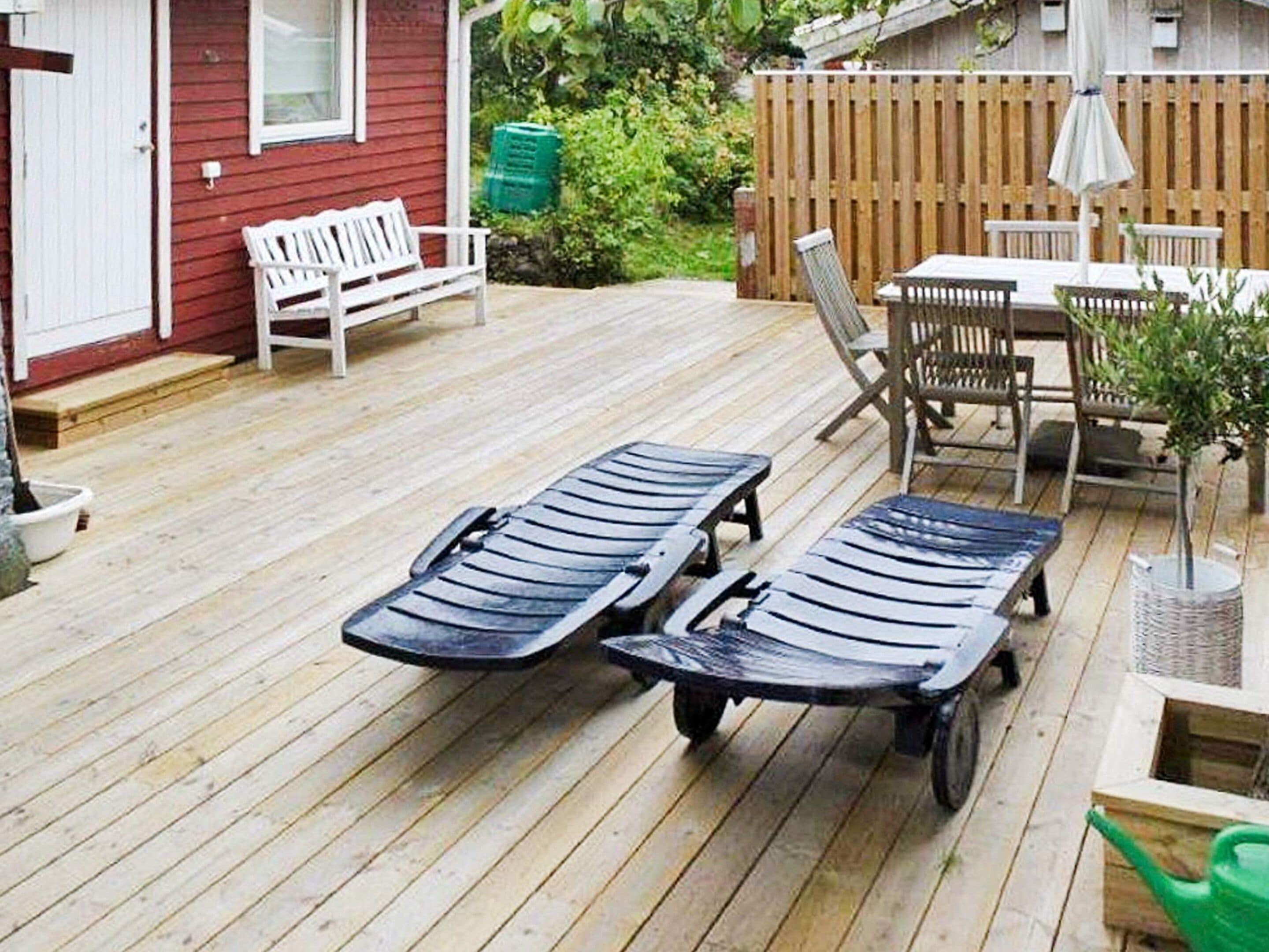 A wooden deck with two lounge chairs and a table with chairs.