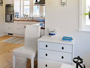 A modern kitchen with white cabinetry, a built-in oven, and a window with a view. - Holiday Home in Dyrön (Roennaeng)