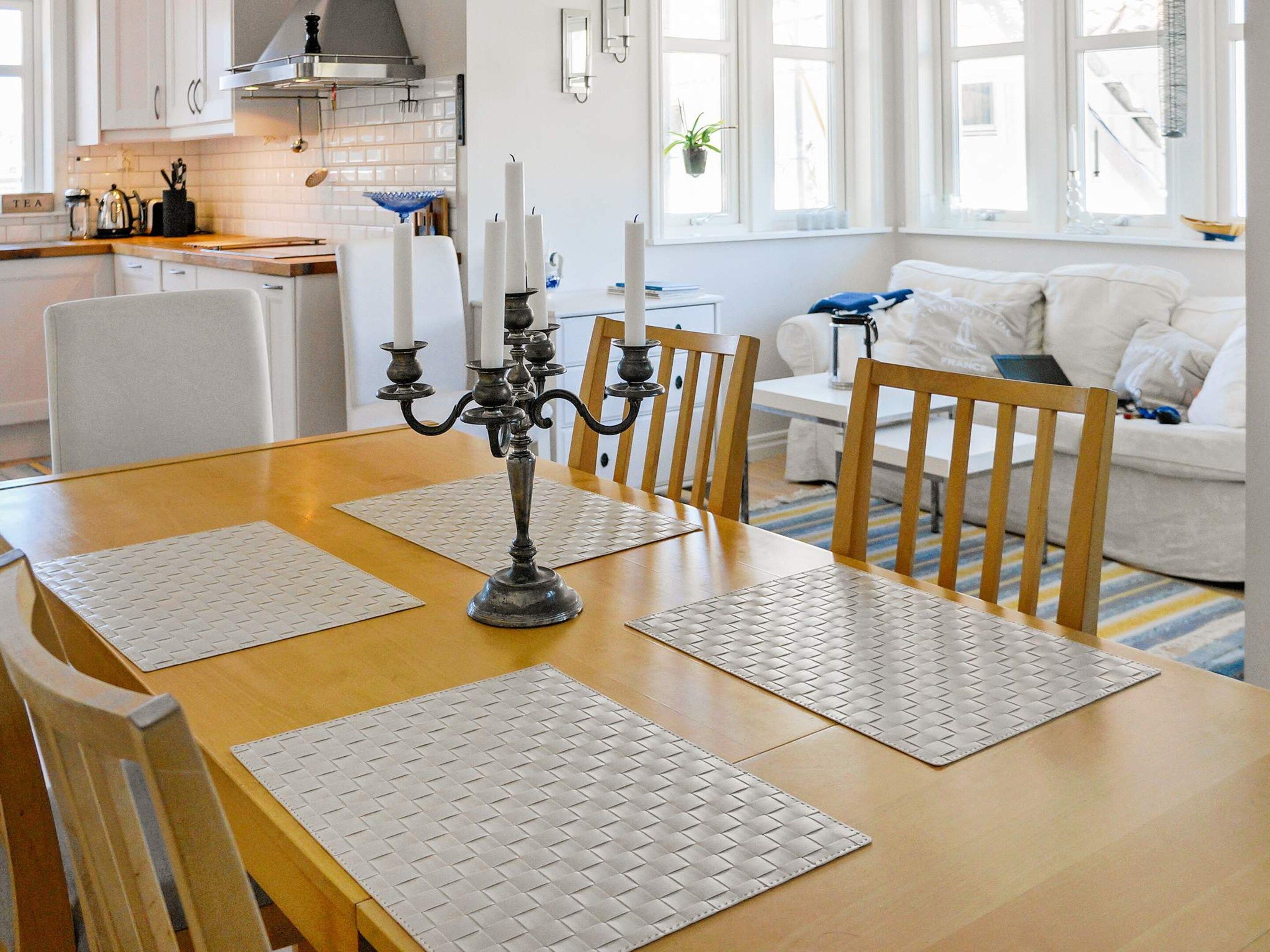 Un comedor con una mesa de madera, cuatro sillas y un candelabro como centro de mesa.