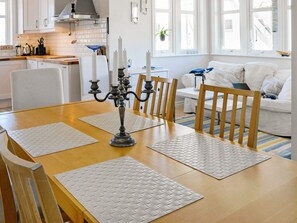 A dining area with a wooden table, four chairs, and a candelabra centerpiece. - Holiday Home in Dyrön (Roennaeng)