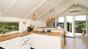 A modern kitchen with white cabinetry, wooden countertops, and pendant lighting.